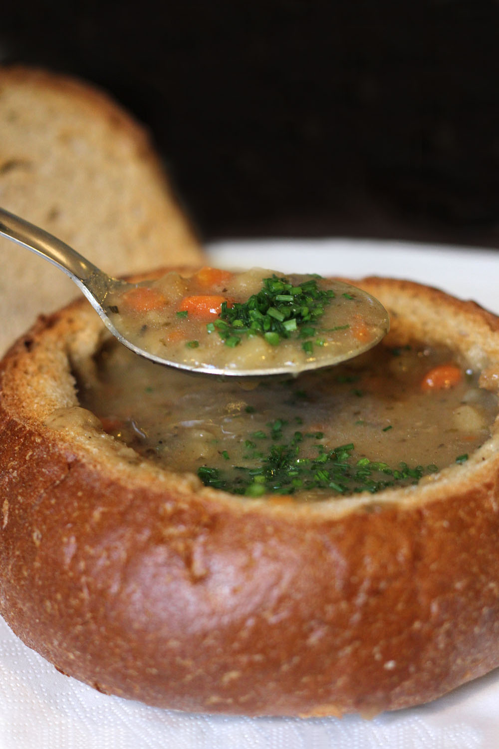 Classic Bohemian potato soup made from potatoes, vegetables, ceps, garlic and marjoram, served in the crust of a hollow loaf