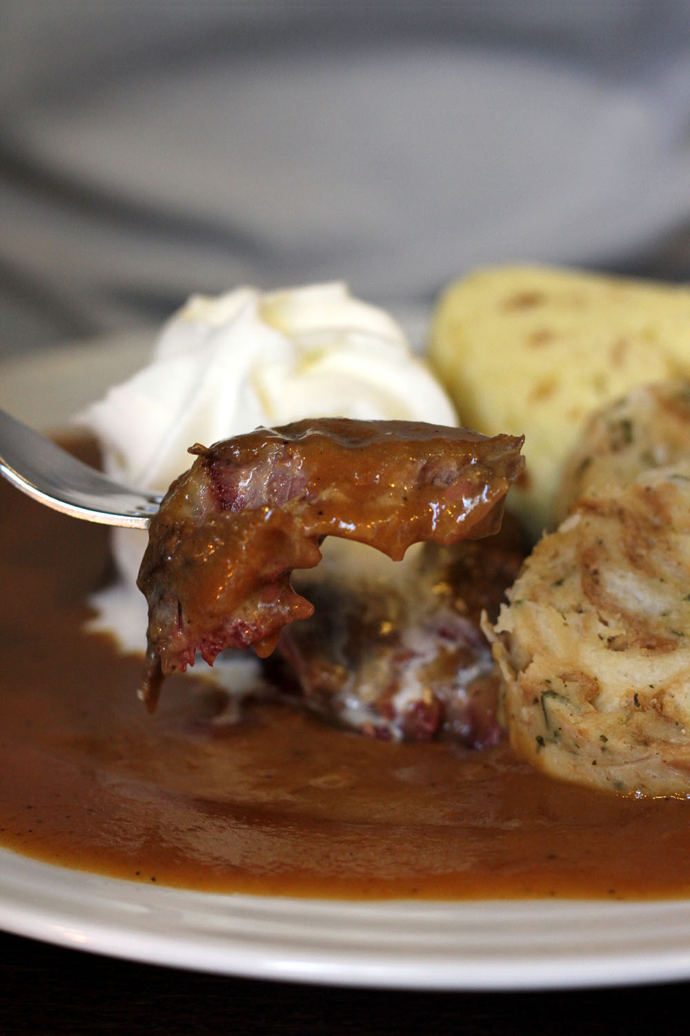 Larded beef in creamy sauce: braised and served with bread and Karlovy Vary dumplings, cranberries, lemon and cream